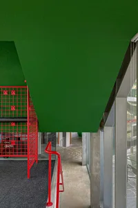 A modern corridor featuring metallic red railings and a green ceiling.