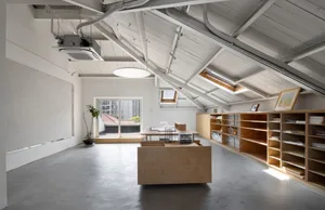 Modern, open-concept office space with industrial design elements, concrete flooring, wooden furniture, and white walls.