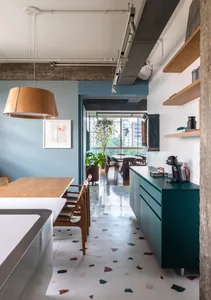 Modern kitchen with wood dining table, concrete backsplash, and terrazzo floor