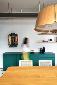 Modern kitchen with teal cabinets, wooden table, and hanging light fixture