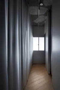 A minimalist interior with white curtains and light-colored wooden flooring.