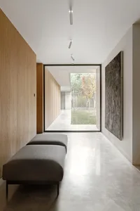A modern interior design featuring a minimalist corridor with concrete flooring, wooden walls, and a large window overlooking