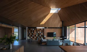 A modern living room featuring wooden walls and floor, with a bookcase, sofa, and TV.