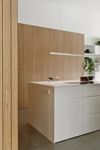A modern residential kitchen with wooden walls and white cabinetry.