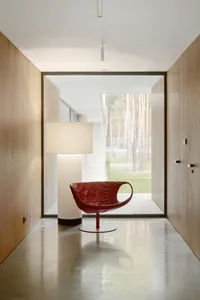 A modern residential lounge featuring a red leather armchair and a white floor lamp.