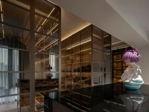 A stylish glass-walled closet with an artistic statue standing on a pedestal within it.