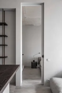 A minimalist bedroom with concrete walls and floors, featuring dark wood furniture and a simple, sleek design.