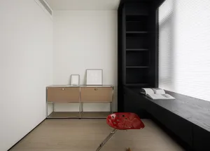 A minimalist home office featuring modern materials and a window seat with a red chair.