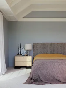 極簡風格臥室，床頭板採用布料包覆，搭配木質床邊桌與一盞燈具。