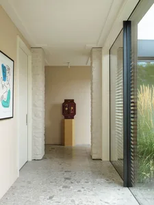 A modern industrial interior with concrete pillars, minimalist decor, and a large glass wall.