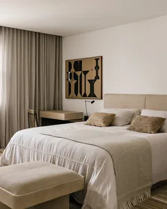 A minimalist bedroom featuring textured fabric bedding and a simple, geometric artwork on the wall.