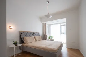 Minimalist bedroom with fabric bed and wooden floor.