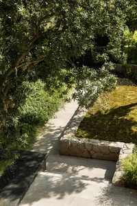 A modern landscape pathway made of stone pavers surrounded by greenery and trees.