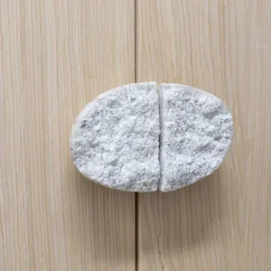 A modern, oval-shaped marble door handle attached to a light-colored wooden door.