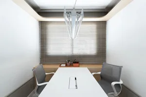 A modern office space with a minimalist design, featuring a white table and gray chairs with a wooden backdrop.