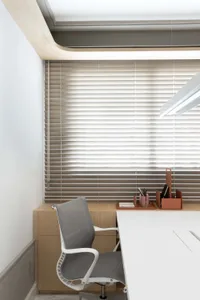 A modern office with minimalist design featuring a wooden desk, metal ring, and contemporary armchair with shaded blinds.