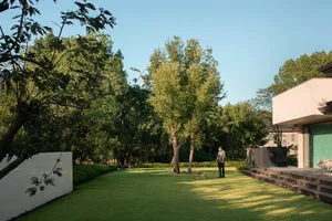 Residential outdoor space featuring lush lawns, concrete pathways, and a modern house with large windows.