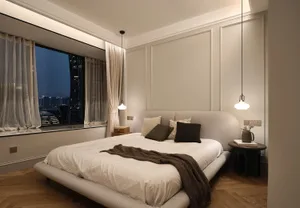 A minimalist bedroom featuring a textured fabric bed set against paneled beige walls.