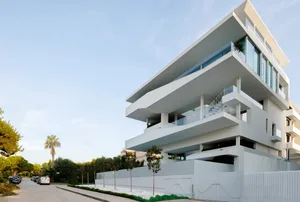 Modern apartment building with white concrete exterior and large balconies.