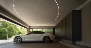 Modern car parked in a sleek, contemporary car port with concrete walls and circular lighting fixture