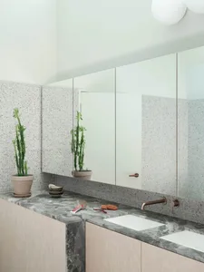 A modern bathroom featuring a terrazzo countertop with two sinks, a large mirror, and minimalist design.
