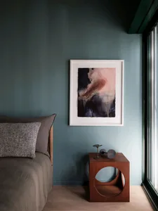Modern bedroom featuring a wooden nightstand with abstract art and a cozy bed.