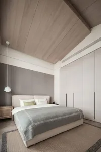 A minimalist bedroom with a white upholstered bed, textured fabric blanket, wooden finished ceiling, and a light-colored rug.