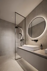 A modern bathroom featuring a minimalist design with concrete walls and floor, a white rectangular sink, and circular mirror 