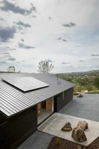 A minimalist residential exterior with a metal roof and stone features.