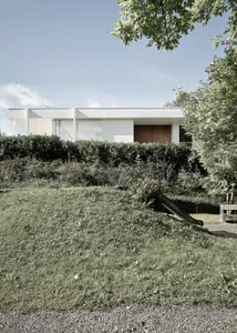 Modern, minimalist house exterior featuring large glass panels and concrete elements.