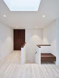 Modern minimalist hallway with white walls, marble flooring, and wooden accents.