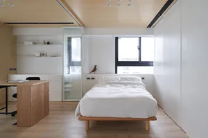 A modern bedroom featuring white furniture and wooden details.