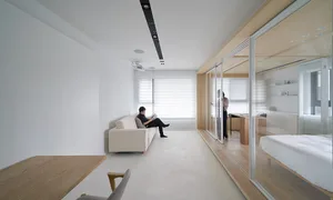 Modern minimalist living room with white furniture, wood accents, and white walls.