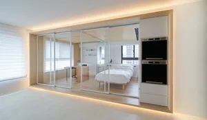 Modern white bedroom with glass partition, bed, and desk.