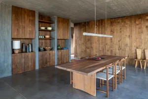 An industrial residential dining room with wooden furniture and concrete walls.