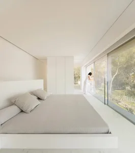 A modern bedroom featuring glass walls and a concrete floor.