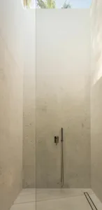 Modern minimalist bathroom with white marble walls and floor, featuring a sleek shower head.