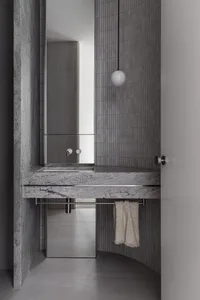 Modern bathroom featuring a gray granite countertop with a hanging light fixture and a towel rack.
