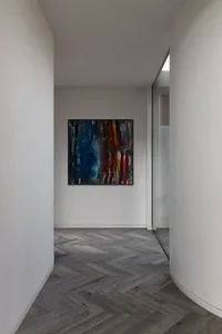 A modern corridor featuring a wooden floor and an abstract painting on the wall.