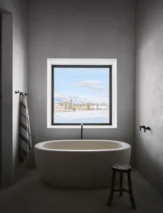 Modern bathroom with a concrete bathtub, designed with a minimalist aesthetic, featuring a window with a scenic view.