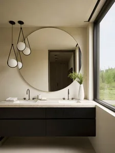 Modern black and white bathroom interior with minimalist design, large round mirror, double sinks, and natural light.