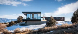 A modern residential architecture with glass walls and concrete foundation.