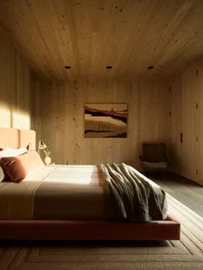 A modern bedroom with wooden walls, featuring a wooden bed and a painting on the wall.