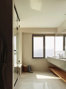 Modern minimalist bathroom with large window, marble tile flooring, and floating sink.