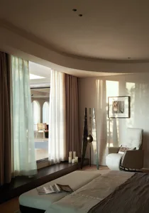 Modern, minimalist bedroom with neutral-toned furniture and soft lighting.