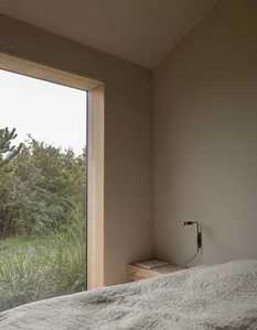 A minimalist bedroom with natural wood accents and grey fabric bedding