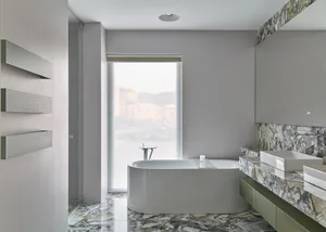Modern industrial bathroom featuring a white freestanding tub with a marble floor and countertop.
