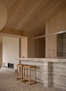 A minimalist kitchen with a stone countertop and wooden stools.