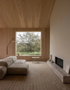 Modern minimalist residential interior featuring wood accents and a large window with a view of greenery.