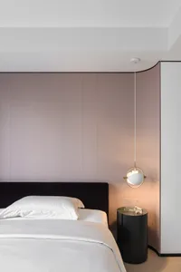 A modern bedroom featuring a fabric upholstered headboard and a white bed with white linens.